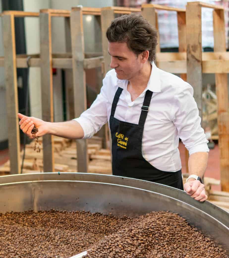 Kaffeeröster prüft frisch geröstete Bohnen im Holzfeuer-Trommelröster